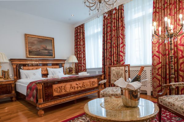 Königliche Suite mit rot-goldenem, reich verziertem Doppelbett und antiken Möbeln.