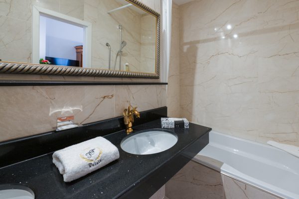 Nahaufnahme eines luxuriösen Waschtisches aus schwarzem Marmor mit goldenen Schwanen-Wasserhähnen.