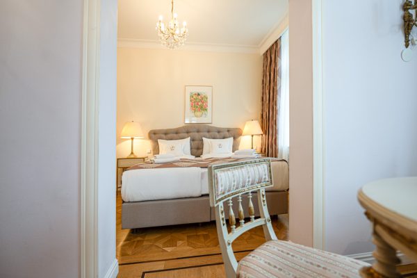 Einblick in helle königliche Suite mit modernem Bett und antikem Mobiliar.