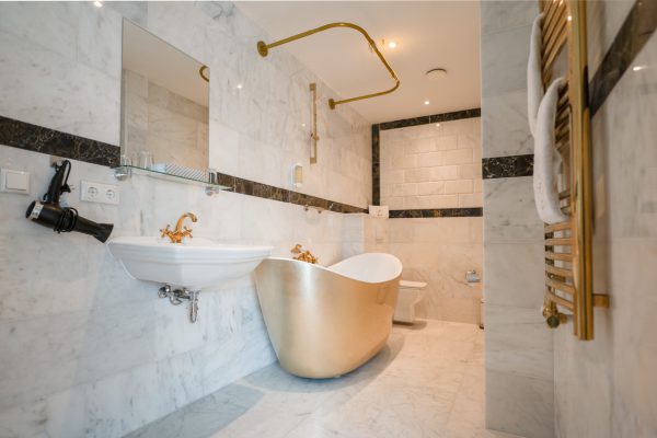 Luxuriöses weißes Badezimmer mit goldener Badewanne und goldenen Wasserhähnen
